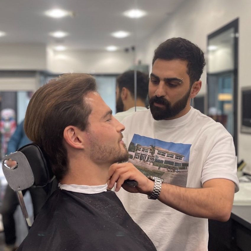 A barber shaping a client's beard at Modern Barbers, Leeds
